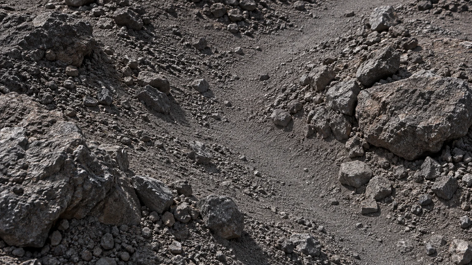 A narrow patch of fine gray-brown regolith winding between low stones. An artistic reconstruction of Lysithea; local detail, lighting and viewpoint are imagined.