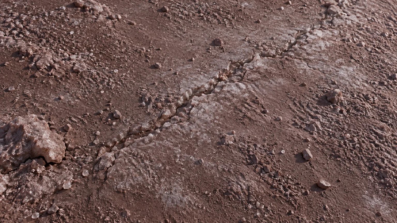 Muted reddish icy regolith with sparse pale grains and a shallow seam. An artistic reconstruction of Quaoar; local detail, lighting and viewpoint are imagined. The depicted environment is a possibility, not an observed surface or weather map.